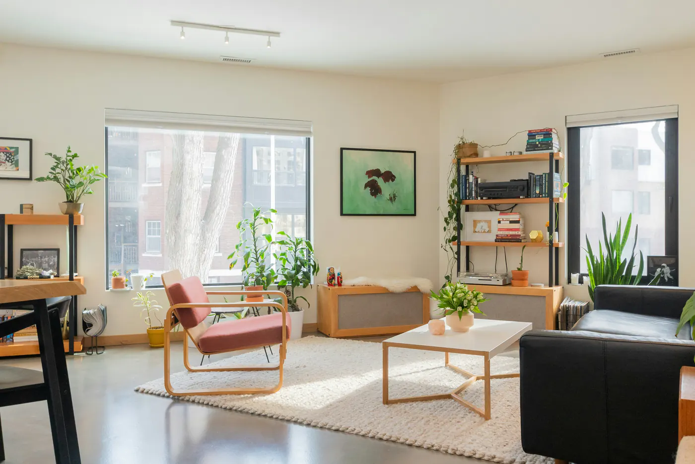 Hell saniertes Wohnzimmer mit großen Fenstern, Designmöbeln und Pflanzen